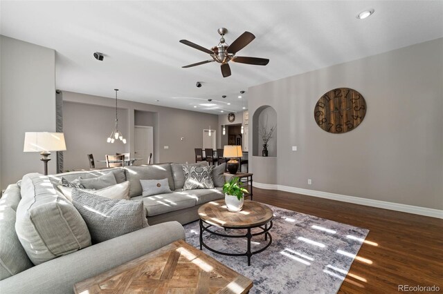 living room featuring baseboards, wood finished floors, ceiling fan, arched walkways, and recessed lighting