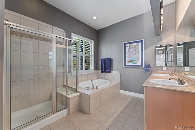 bathroom featuring tile patterned flooring, a stall shower, a garden tub, baseboards, and double vanity
