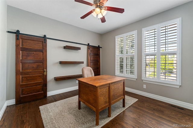 home office with a barn door, ceiling fan, baseboards, and dark wood-style floors