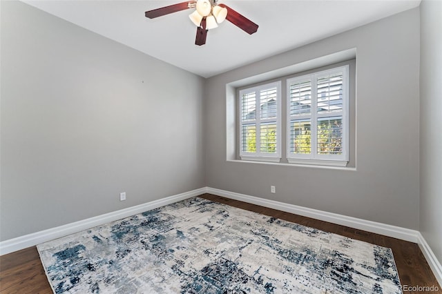 empty room featuring a ceiling fan, baseboards, and dark wood-type flooring