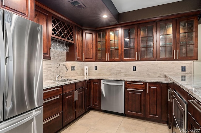 kitchen featuring appliances with stainless steel finishes, a sink, light tile patterned flooring, recessed lighting, and backsplash