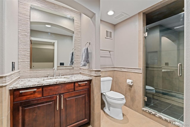 full bath featuring tile walls, toilet, a shower stall, vanity, and tile patterned floors