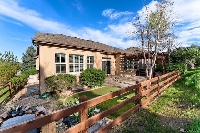 rear view of house with stucco siding and roof with shingles