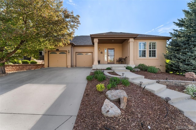 view of front of home featuring an attached garage, driveway, stucco siding, and roof with shingles