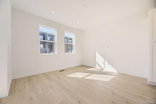 spare room with recessed lighting, light wood-type flooring, visible vents, and baseboards