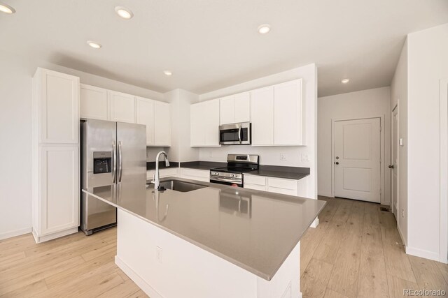 kitchen with stainless steel appliances, white cabinetry, a sink, and light wood-style flooring