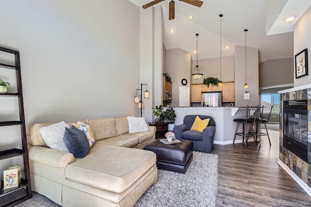 living room with high vaulted ceiling, ceiling fan, wood finished floors, a multi sided fireplace, and baseboards