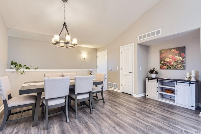 dining space featuring a chandelier, wood finished floors, baseboards, and vaulted ceiling