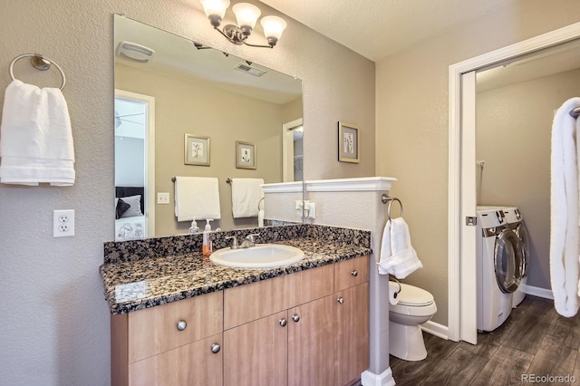 ensuite bathroom with washer and dryer, wood finished floors, toilet, vanity, and baseboards