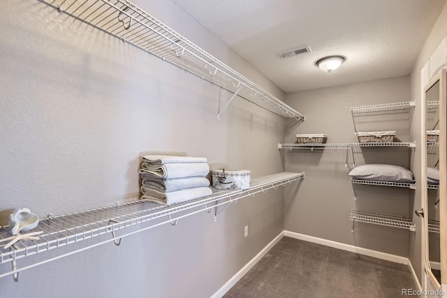 walk in closet featuring dark carpet