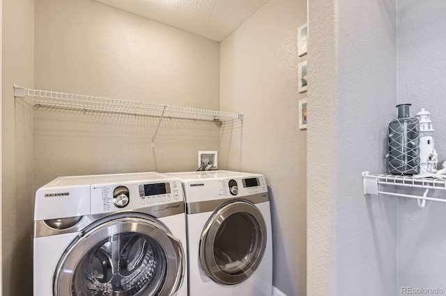 laundry area with washing machine and dryer and a textured wall