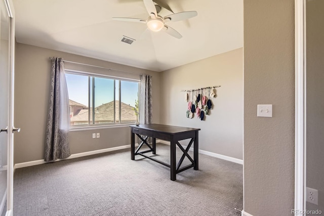 carpeted office space featuring ceiling fan and baseboards
