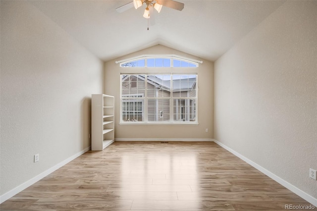 empty room featuring a ceiling fan, vaulted ceiling, baseboards, and wood finished floors