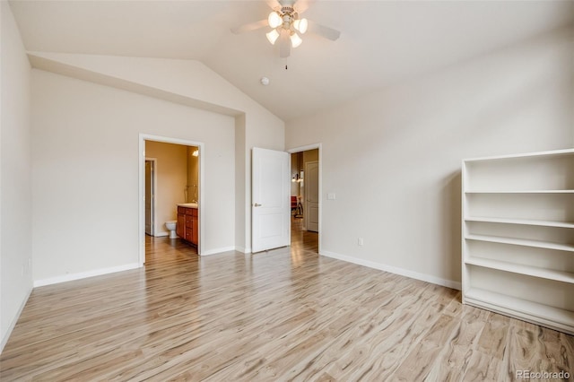 interior space with light wood finished floors, baseboards, vaulted ceiling, and ensuite bathroom