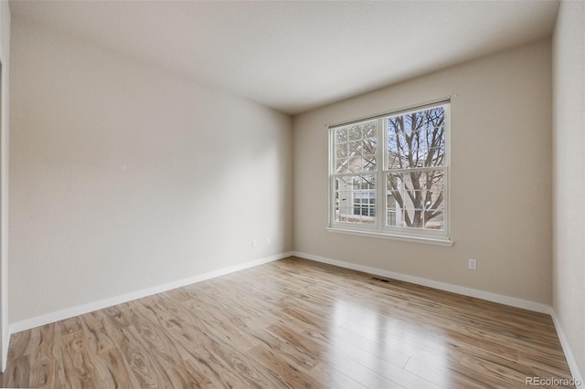 empty room with baseboards, visible vents, and wood finished floors