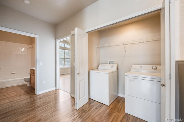 washroom featuring light wood-type flooring, laundry area, baseboards, and independent washer and dryer