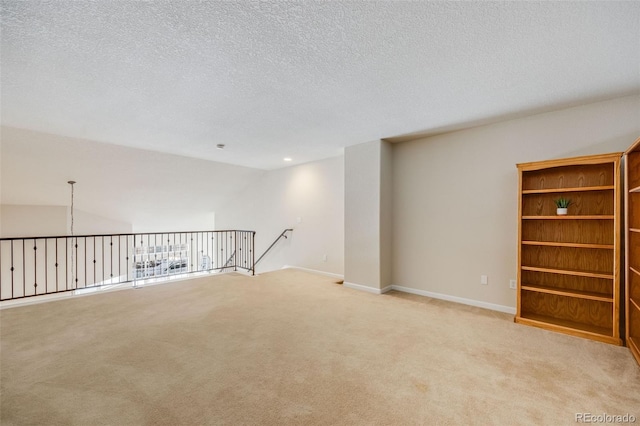 spare room with a textured ceiling, baseboards, and light colored carpet