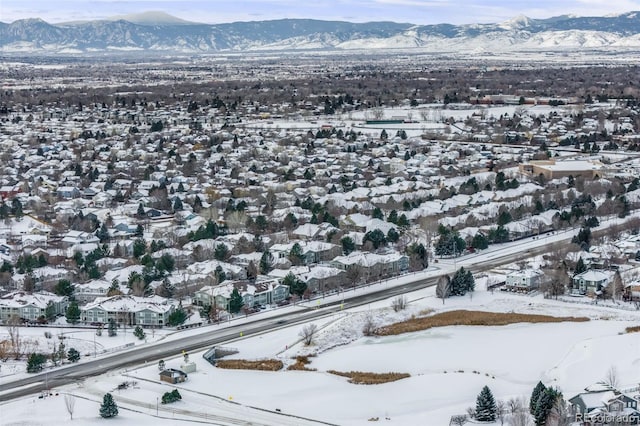 snowy aerial view featuring a mountain view and a residential view