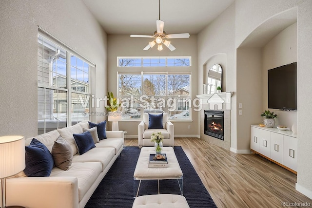 living area featuring baseboards, a fireplace, a wealth of natural light, and light wood-style floors