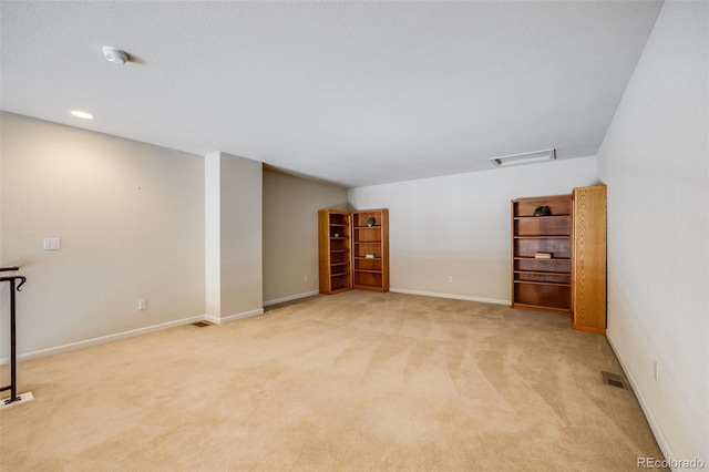 empty room featuring baseboards, visible vents, and light colored carpet