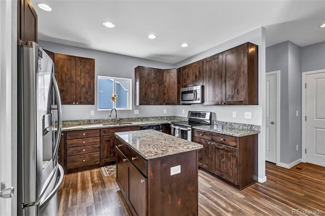 kitchen with dark brown cabinetry, sink, appliances with stainless steel finishes, dark hardwood / wood-style flooring, and a kitchen island