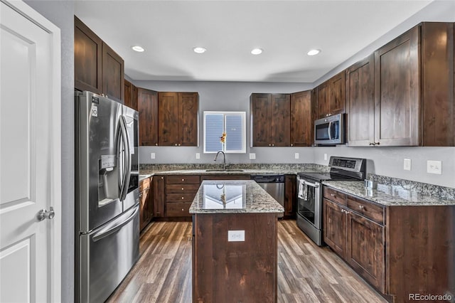 kitchen featuring a kitchen island, sink, stainless steel appliances, light stone countertops, and dark brown cabinets