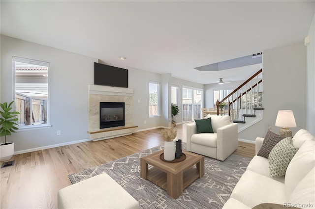 living room featuring a tile fireplace, hardwood / wood-style floors, and ceiling fan