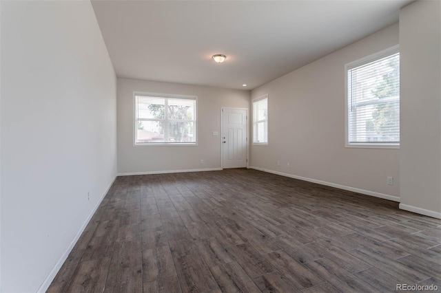 spare room with plenty of natural light and dark wood-type flooring