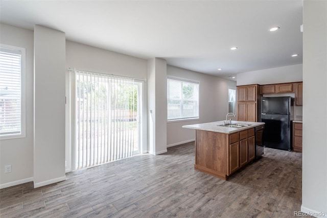 kitchen with black appliances, wood-type flooring, an island with sink, and a wealth of natural light