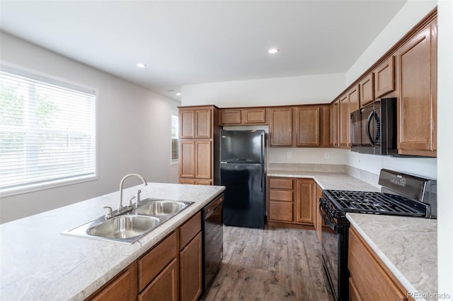 kitchen featuring light wood-type flooring, black appliances, and sink