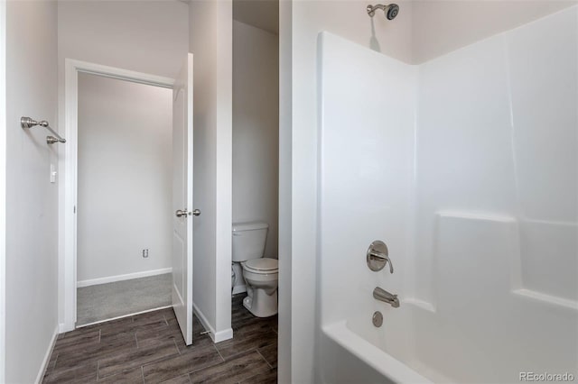 bathroom with hardwood / wood-style flooring, toilet, and washtub / shower combination