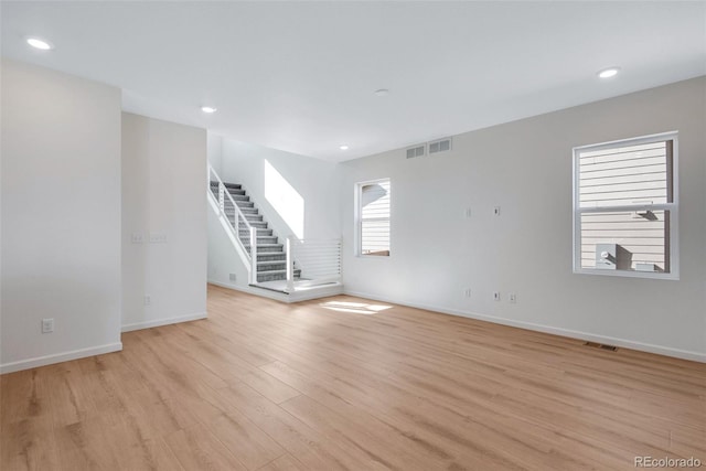 unfurnished room with light wood finished floors, baseboards, stairway, and recessed lighting