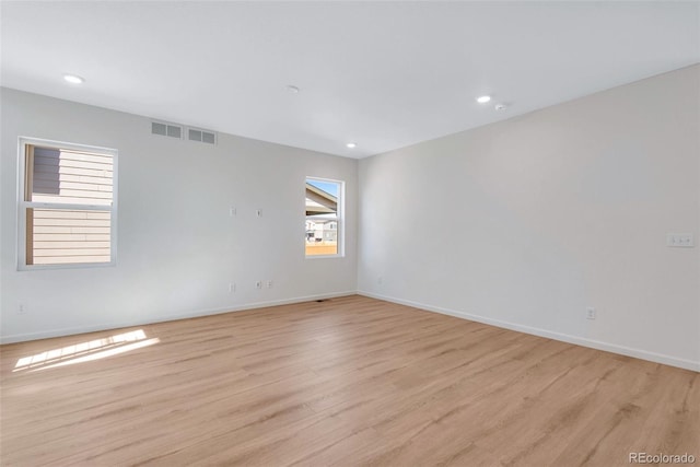 spare room featuring light wood-style floors, baseboards, and recessed lighting