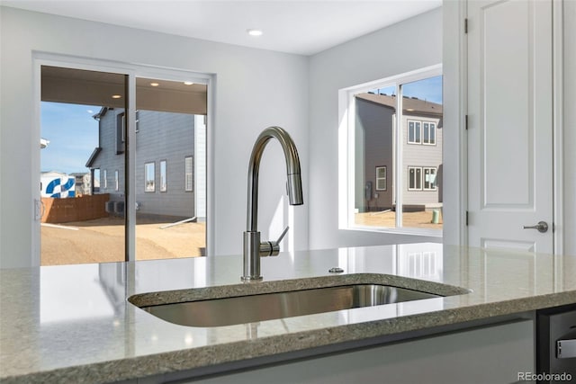 kitchen view of a sink, stone countertops, and recessed lighting