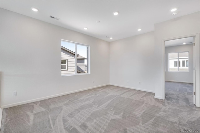 unfurnished room featuring light colored carpet, plenty of natural light, baseboards, and recessed lighting