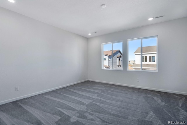 spare room featuring dark carpet, baseboards, and recessed lighting