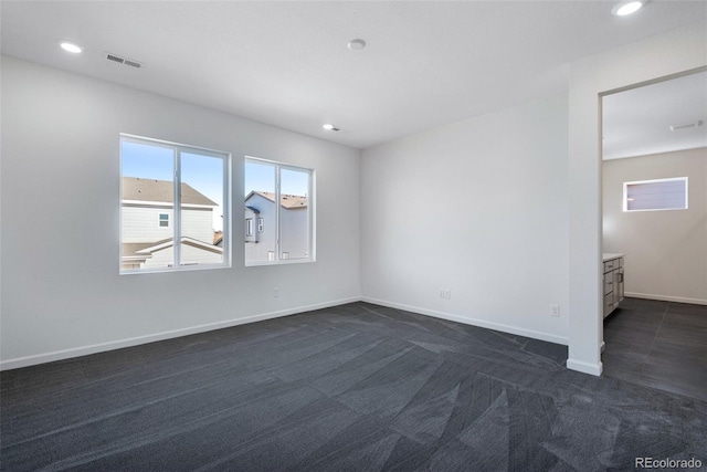 empty room with dark carpet, baseboards, and recessed lighting