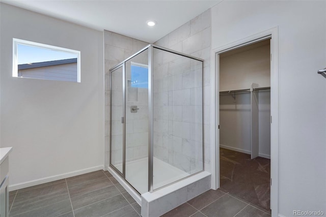 full bath featuring a stall shower, a walk in closet, recessed lighting, baseboards, and tile patterned flooring