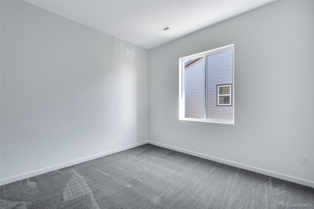 spare room featuring dark carpet and baseboards
