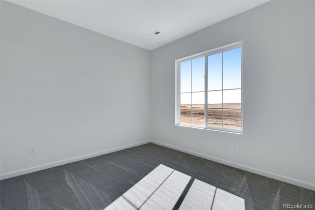 unfurnished room featuring dark colored carpet and baseboards
