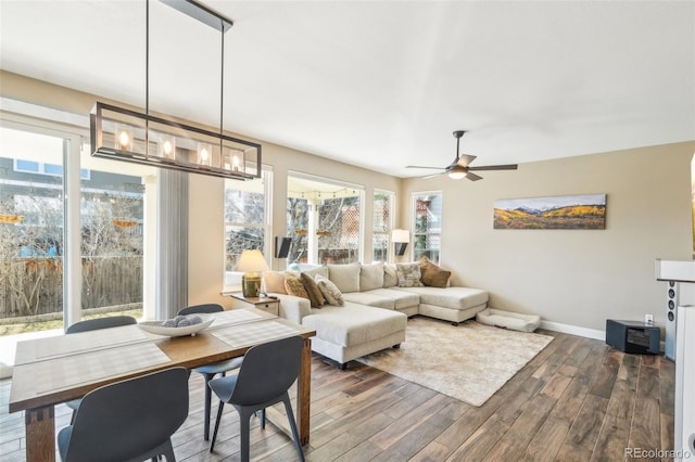 living area featuring baseboards, dark wood-style flooring, and ceiling fan with notable chandelier