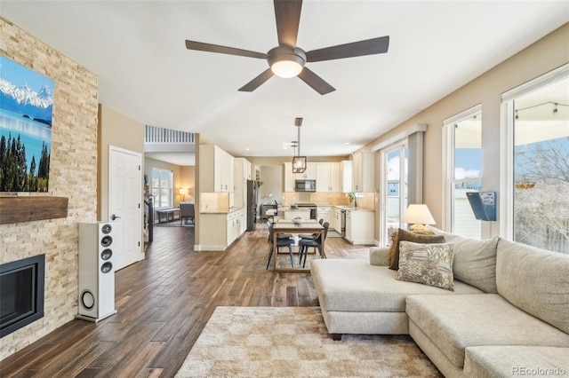 living room with dark wood finished floors, a fireplace, visible vents, and ceiling fan