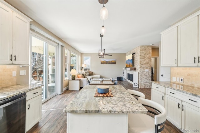 kitchen with dishwasher, wood finished floors, open floor plan, and a large fireplace