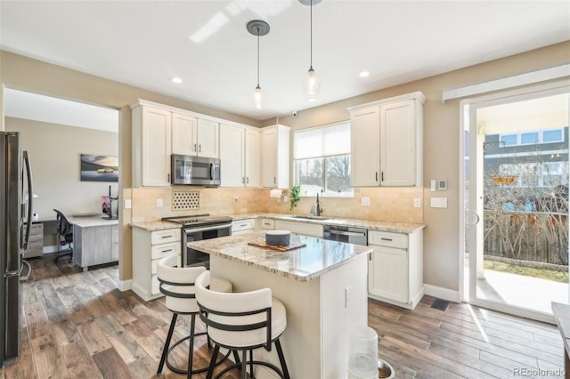 kitchen featuring decorative backsplash, stainless steel appliances, wood finished floors, and a sink