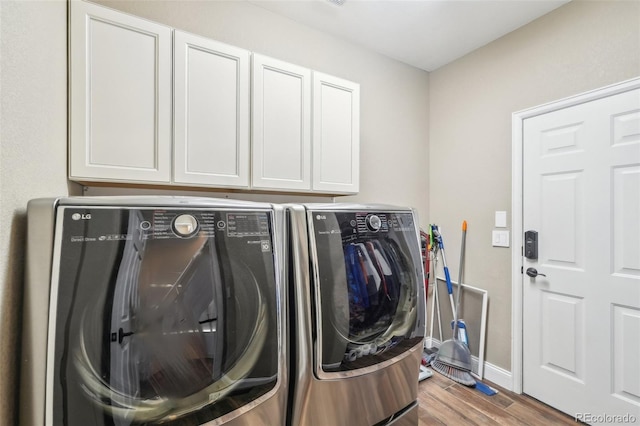 laundry area with cabinet space, baseboards, wood finished floors, and washing machine and dryer