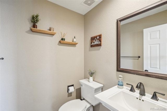 bathroom with toilet, visible vents, and a sink