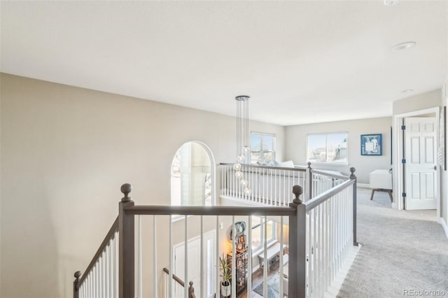 hall with baseboards, an upstairs landing, and carpet flooring