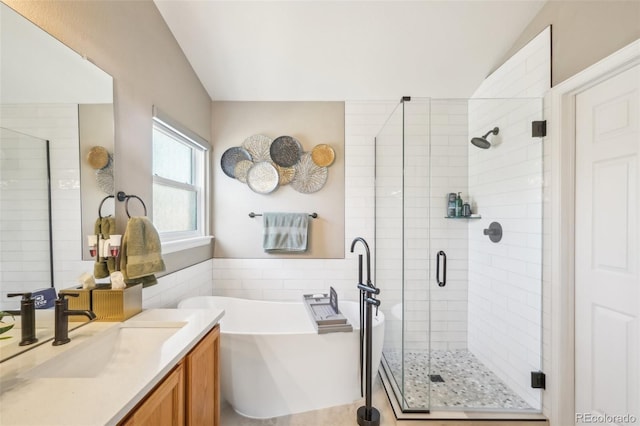 bathroom with vanity, a freestanding tub, a shower stall, wainscoting, and tile walls