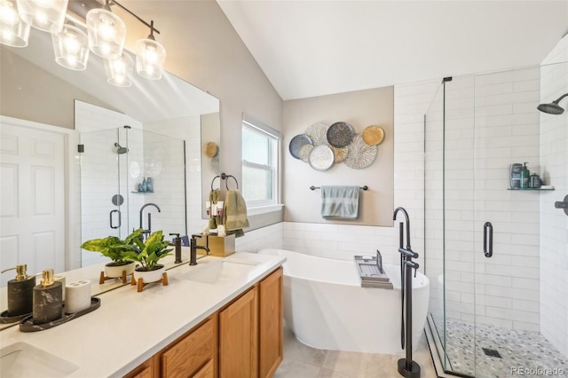 bathroom featuring a shower stall, double vanity, vaulted ceiling, a freestanding tub, and a sink