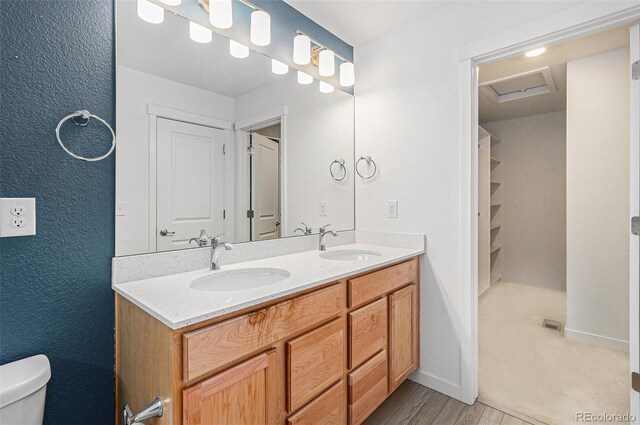 9757 Ash Ln, Thornton, CO 80229 - bathroom featuring toilet, double vanity, wood finished floors, and baseboards